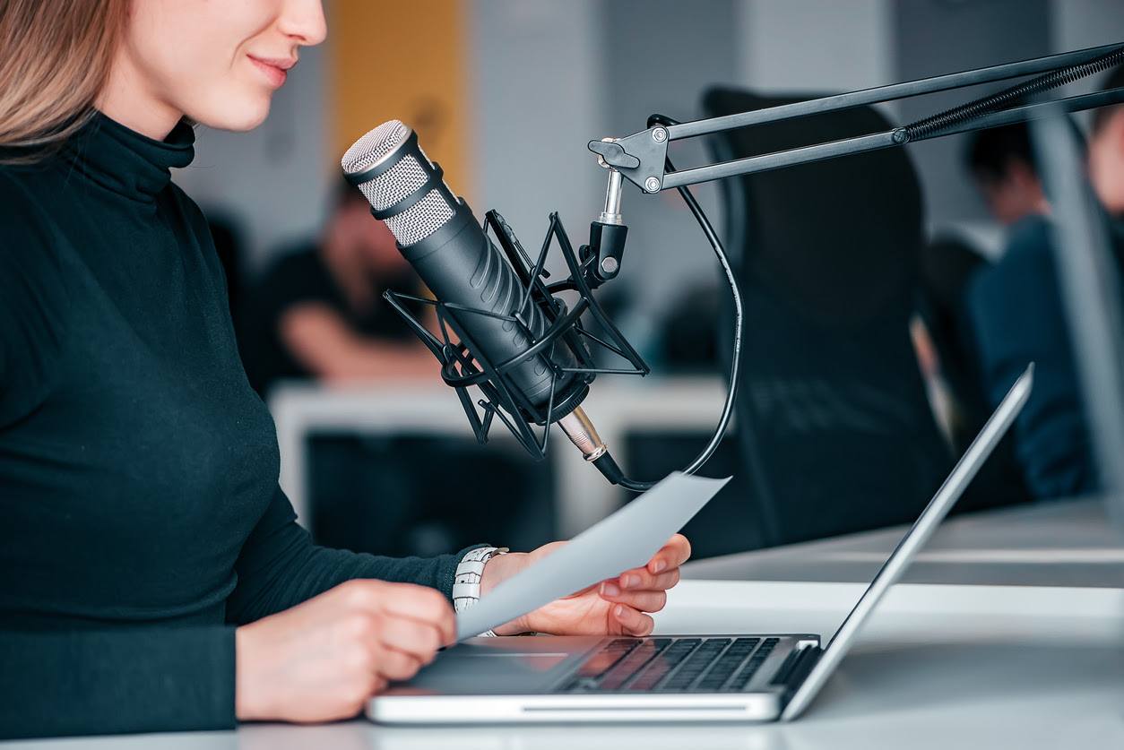 woman using public address system in an office while holding a paper